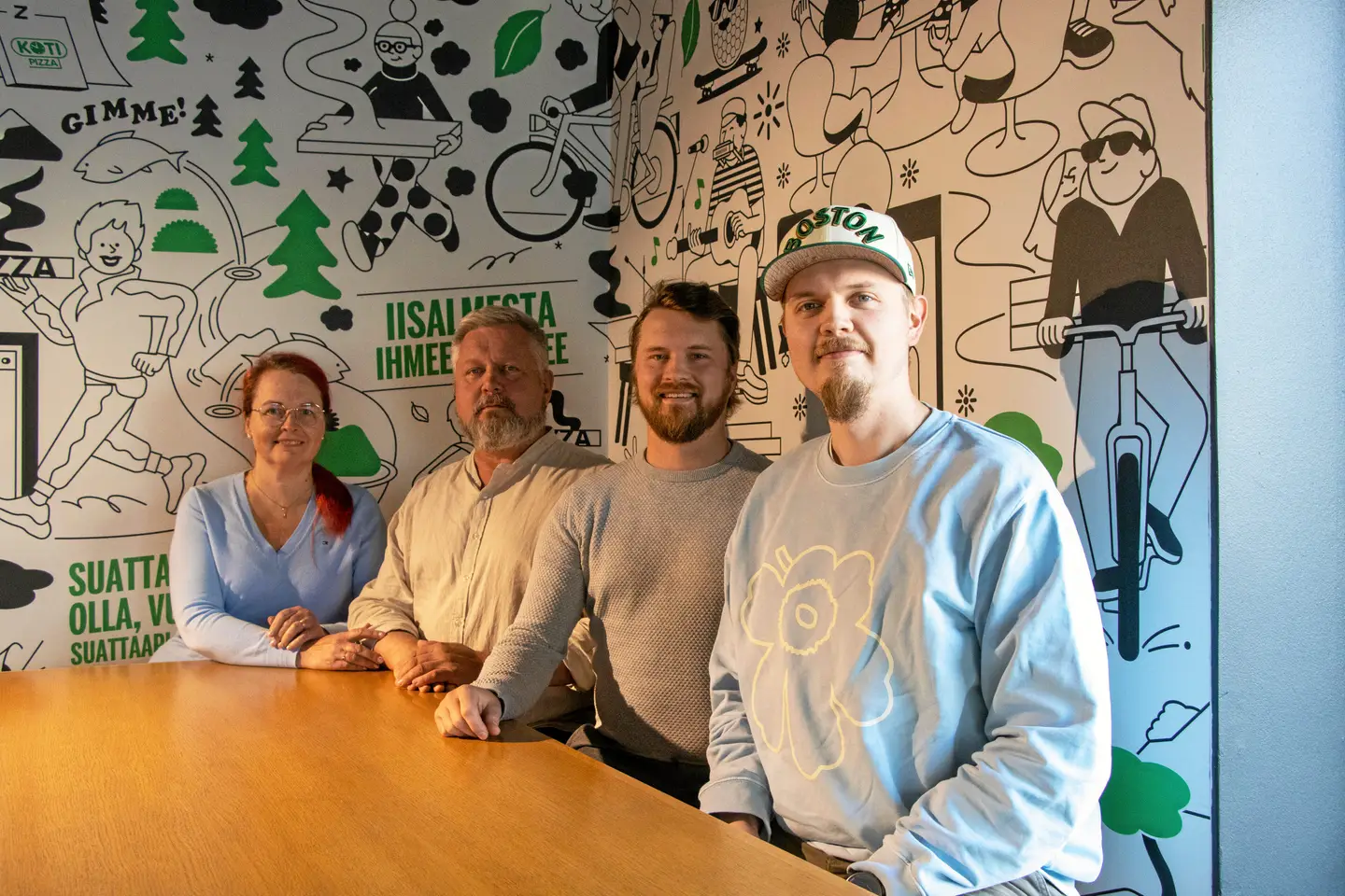 K&R Riiholan väkeä Kotipizzan seinämaalauksen edessä